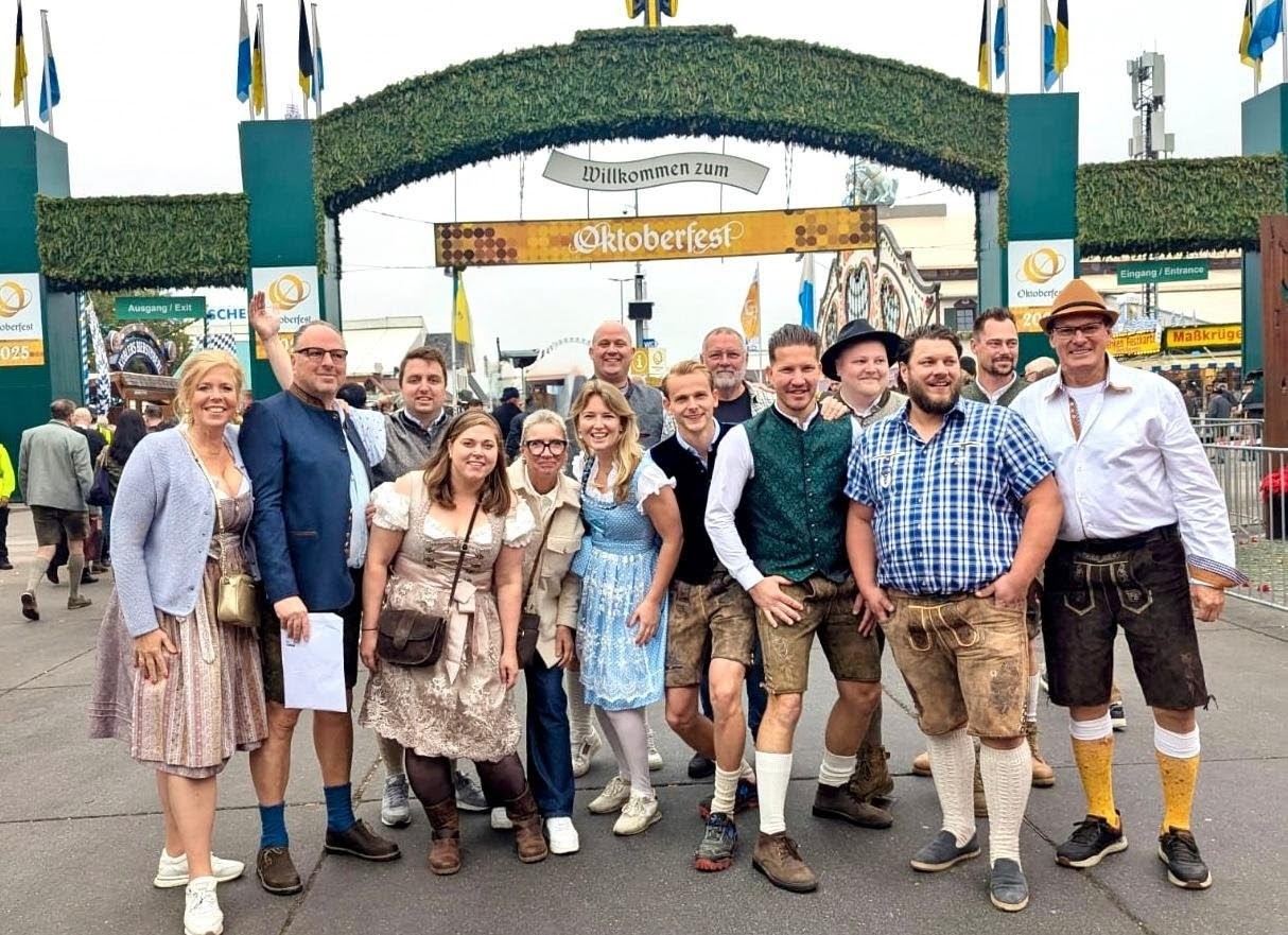 De groep in klederdracht bij de ingang van het Oktoberfest